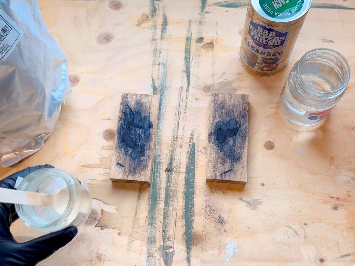 Side-by-side comparison of two oak blocks showing oxidised black stains before stain removers are applied. Both blocks have visible discolouration from steel wool tannin reaction.